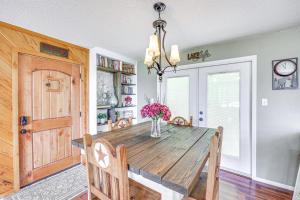 a dining room with a wooden table with a vase of flowers at Treetop Hideaway with Lake Views and Fire Pit! in Fairfield Bay