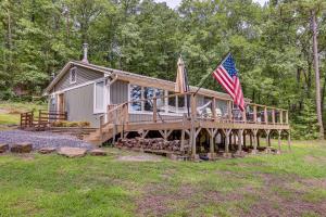 a house with a deck with an american flag on it at Treetop Hideaway with Lake Views and Fire Pit! in Fairfield Bay