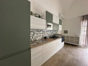 a kitchen with white and green cabinets and wooden floors at Holiday House Marsala in Marsala