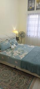a bedroom with a bed with a blue blanket and a window at Homestay Cikgu-formuslimonly in Pasir Gudang
