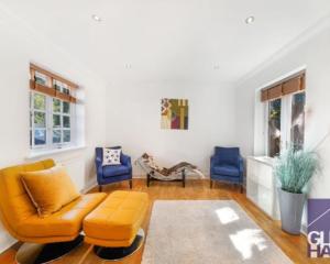 a living room with an orange couch and two blue chairs at The Mews, N14 in New Southgate