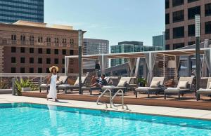 a woman standing next to a swimming pool on a building at Stunning 3BR High Rise Pool, Spa & Rooftop Views in Los Angeles