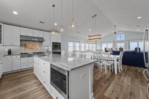 a kitchen and dining room with white cabinets and a table at 8478 - Seas the Breeze II in Avon
