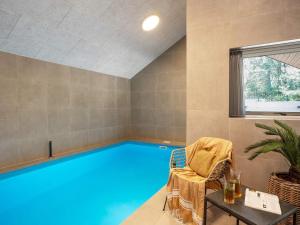 a large swimming pool in a room with a chair at 5 star holiday home in Rømø in Kongsmark