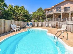 a swimming pool with chairs and a fence at 3041 - The Beach House in Southern Shores