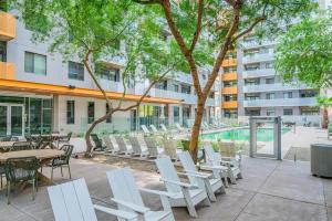 a patio with white chairs and tables and a pool at Spacious 2BR Apt with Gym Pool Parking in Phoenix
