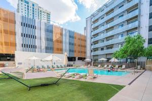 a pool with chairs and umbrellas next to a building at Spacious 2BR Apt with Gym Pool Parking in Phoenix