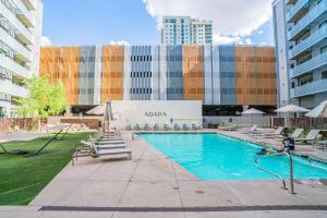 a swimming pool with chairs and a building at Spacious 2BR Apt with Gym Pool Parking in Phoenix +58 photos
