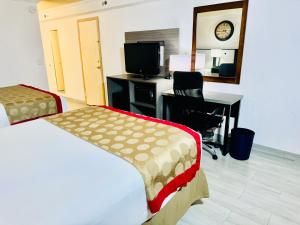 a hotel room with a bed and a desk with a computer at Ramada by Wyndham Birmingham Airport in Birmingham