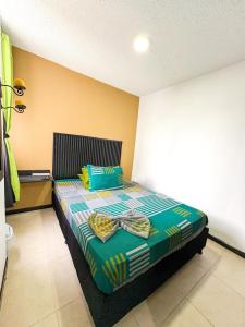 a bedroom with a bed with a green and blue comforter at Ciudadela Santa fe Apartasol 4 A 2 in Santa Fe de Antioquia +36 photos