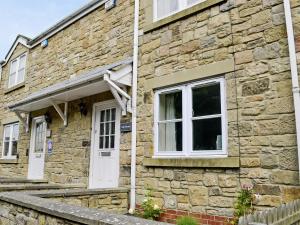 a stone house with a white door and windows at Teal Cottage in Embleton +2 photos