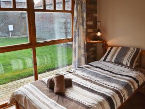 a bedroom with a bed and a large window at Ploughman's Cottage in Flamborough