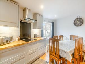 a kitchen with white cabinets and a table and a dining room at The Sail Loft in Teignmouth +15 photos