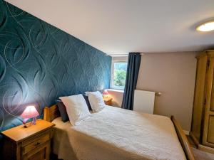 ein Schlafzimmer mit einem Bett mit einer blauen Wand in der Unterkunft Chambre Iris dans bâtisse rénovée au cœur de la nature - FR-1-589-726 in Moyenmoutier