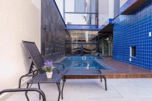 eine Terrasse mit zwei Stühlen und einem Swimmingpool in der Unterkunft HANNA Amsterdam Apart Hotel & Eventos in Florianópolis