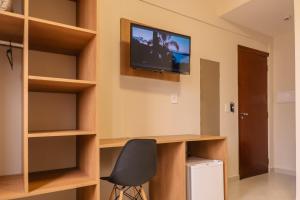 フロリアノポリスにあるHANNA Amsterdam Hotel & Eventosのデスク、壁掛けテレビが備わる客室です。