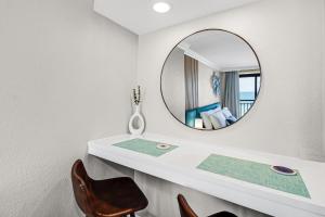 a bathroom with a mirror and a chair at Paradis By Casanita - Oceanfront Lux Designer Suite in Myrtle Beach