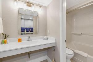 Un baño con lavabo, inodoro y espejo. en Paradis By Casanita - Oceanfront Lux Designer Suite, en Myrtle Beach