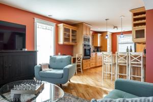 a living room and kitchen with orange walls and blue chairs at Glyn Rhosyn Balcony Riverview in Stratford
