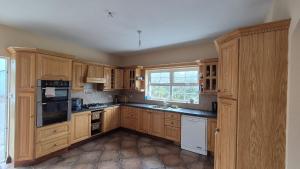 a large kitchen with wooden cabinets and a window at Azure Villa in Carrigaholt