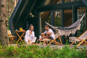 mężczyzna i kobieta siedzący w hamaku przed domem w obiekcie Bajka Resort & GARDEN SPA w mieście Grodziec