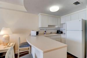 une cuisine avec des armoires blanches et un réfrigérateur blanc dans l'établissement Coastal Views Spacious Beachfront Condo, à Daytona Beach 18 autres photos