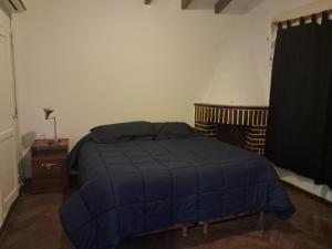 ein Schlafzimmer mit einem Bett mit einer blauen Decke in der Unterkunft La Casa de María Helenra in Alta Gracia
