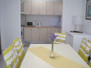 kuchnia ze stołem, na którym stoi wazon z kwiatami w obiekcie Apartment in Zadar - Zadar Riviera 7970 w mieście Zadar