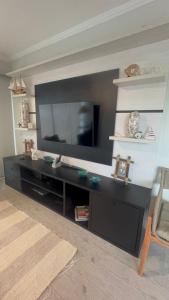 a living room with a black entertainment center with a flat screen tv at Apartamento em Ubatuba com vista para o mar in Ubatuba