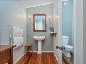 ein Badezimmer mit Waschbecken, Toilette und Spiegel in der Unterkunft Creed Cottage - Whitianga Heritage Retreat in Whitianga + 28 Fotos