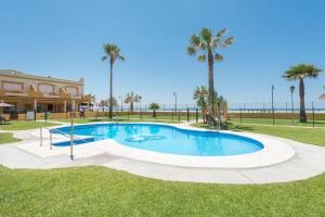 una piscina con palmeras y un edificio en Apartamento Tortuga I, en Tarifa