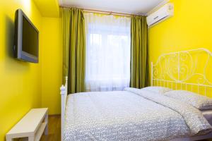 Dormitorio amarillo con cama y TV en Star Apartment On Kyievskaya, en Moscú