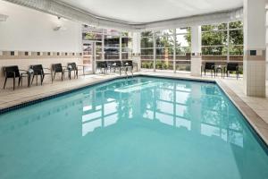 a swimming pool with chairs and tables in a building at Courtyard Minneapolis Maple Grove Arbor Lakes in Maple Grove