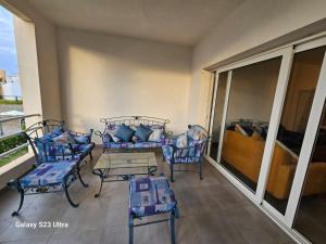 einen Balkon mit Stühlen, einem Tisch und einem Sofa in der Unterkunft Amwaj sidi abed el rahman in Banī Ghālib