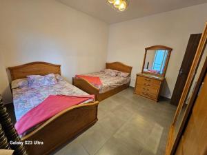 2 Einzelbetten in einem Zimmer mit Spiegel in der Unterkunft Amwaj sidi abed el rahman in Banī Ghālib