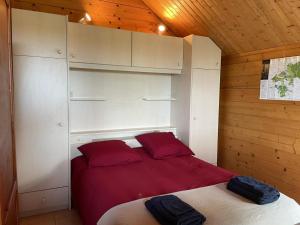una camera da letto con un letto grande con cuscini rossi di Chalet avec Clim, Wi-Fi et Animaux Acceptés à Saint-Bonnet-Tronçais - FR-1-489-445 a Saint-Bonnet-Tronçais
