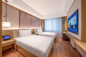 a bedroom with two beds and a flat screen tv at 武汉汉口金融中心万象城漫心酒店 in Wuhan