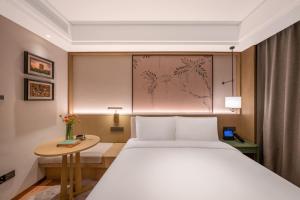 a bedroom with a large white bed and a table at 武汉汉口金融中心万象城漫心酒店 in Wuhan
