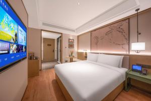 a bedroom with a large bed and a flat screen tv at 武汉汉口金融中心万象城漫心酒店 in Wuhan