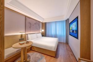 a bedroom with a bed and a table and a tv at 武汉汉口金融中心万象城漫心酒店 in Wuhan