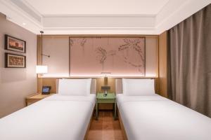 two beds in a room with a painting on the wall at 武汉汉口金融中心万象城漫心酒店 in Wuhan
