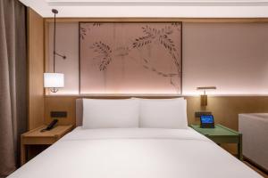 a bedroom with a white bed and a painting on the wall at 武汉汉口金融中心万象城漫心酒店 in Wuhan