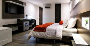 Un dormitorio con una cama, un escritorio y un televisor. en Hotel Loyds, en Medellín
