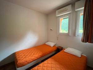 Dos camas en una habitación pequeña con dos ventanas. en Appartement 6 pers avec vue Socoa et terrasse - FR-1-239-1142, en Ciboure
