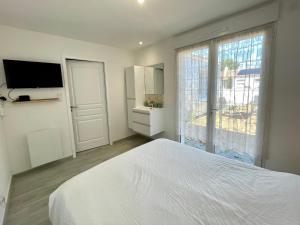 a white bedroom with a bed and a window at Maison rénovée avec WIFI, 700m de la mer - 4 couchages - FR-1-231-341 in Brétignolles-sur-Mer