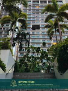 a large building with palm trees in front of it at Novotel Tower at Mandaluyong Rockwell View in Manila