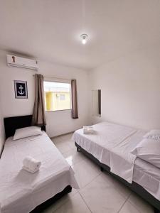 two beds in a white room with a window at Residencia Praia Dos Corais H100 in Santa Cruz Cabrália