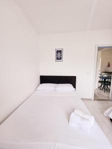 a white bed with two towels on it in a bedroom at Residencia Praia Dos Corais H100 in Santa Cruz Cabrália +3 photos