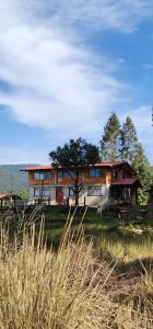 a large house sitting on top of a grass field at Cabaña El Descanso del Carpintero in La Marquesa