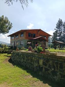 a house with a stone wall in front of it at Cabaña El Descanso del Carpintero in La Marquesa